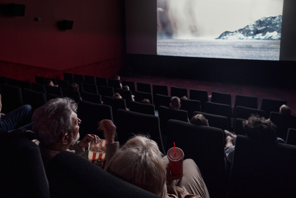 Back view of a mature couple watching a movie in cinema.