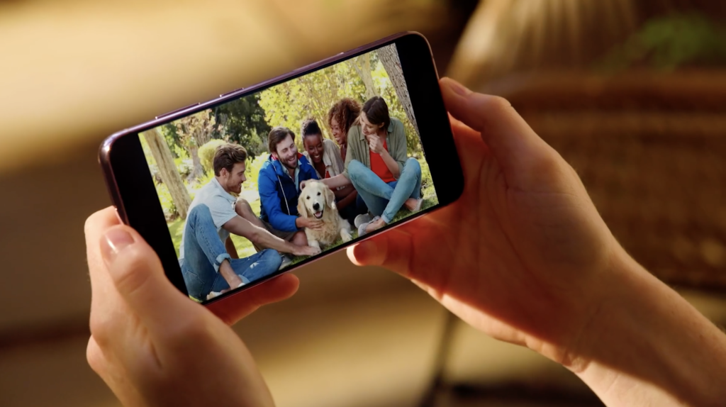 Person holding phone with people on screen