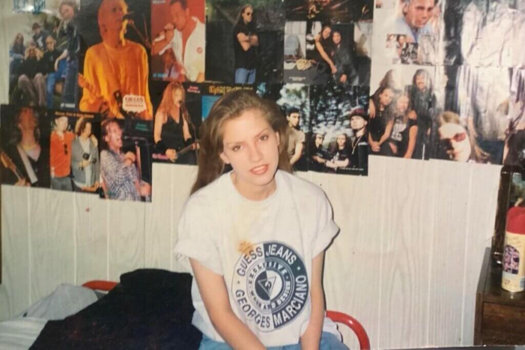 Pretty Blonde Girl with a 1990s look Sitting on Her Bed In her rrom looking at the camera