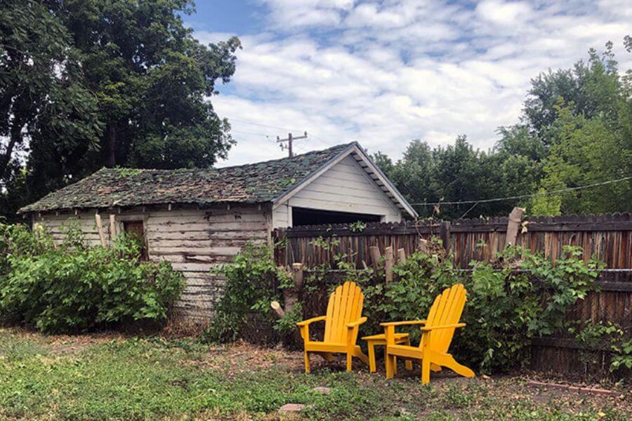 two yellow plastic chairs in a back yard