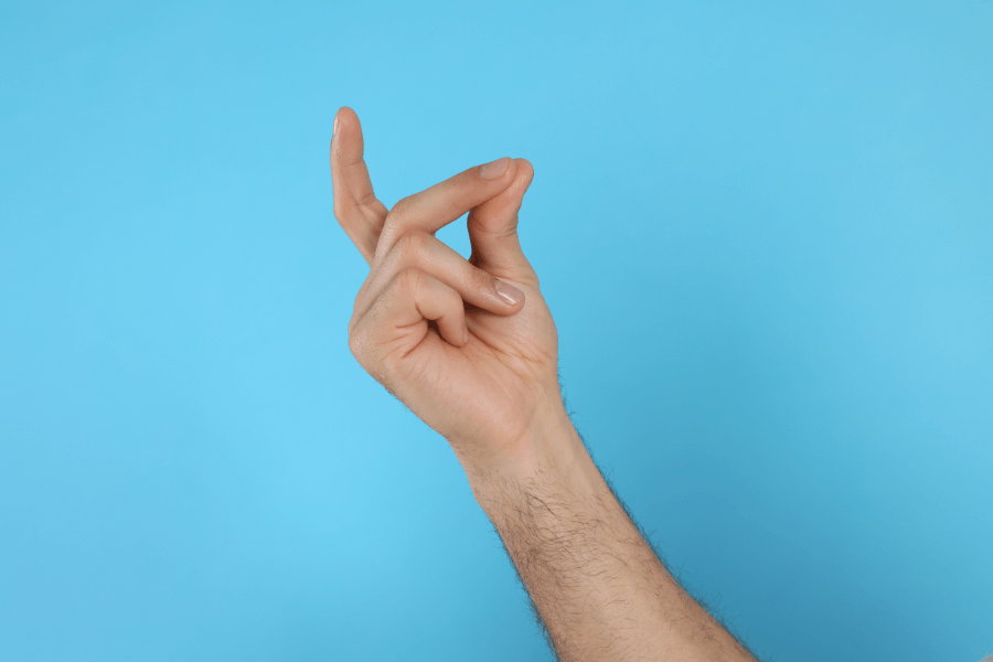 A hand with a light skin tone is shown snapping its fingers against a solid blue background. The arm is slightly bent, and the action is captured mid-snap.